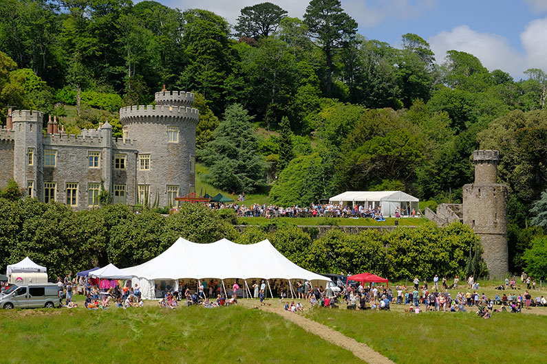 Marquee tent and groups of people outside Caerhays Castle, at the Summer Fete last year
